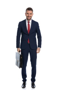 Genç yakışıklı iş adamı elinde bir çantayla poz veriyor ve yüzünde beyaz bir gülümseme var.