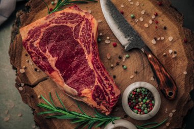 Biberiyeli, tuzlu ve biberiyeli taze biftek masası tahta kesme tahtasında bıçakla sunuluyor. 