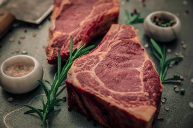 Nadir pişmemiş iki parça biberiyeli kırmızı et ve demir masadaki küçük tuz ve biber kaseleri estetik açıdan yakından görülür.