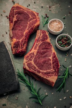 Demir masanın üstünde iki kamış bifteği, biberiyenin yanında da tuz, biber ve satır bıçağı. 