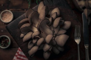 Tahta üzerinde mantar, tuz ve biber ve servis için çatal ve bıçak olan sağlıklı bir yemek.