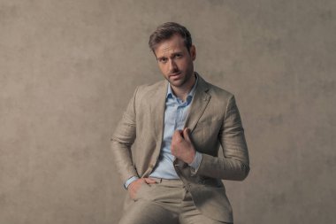 young handsome businessman with attitude is arranging his jacket, putting one hand in pocket