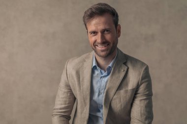 Kameraya gülümseyen ve duvar kağıdına karşı poz veren yakışıklı bir iş adamının portresi.