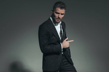 Tıraşlanmamış bir damat portresi zarif bir kravat takmış, parmağıyla işaret ediyor ve havalı ve kendinden emin bir şekilde poz veriyor. 