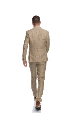 Takım elbiseli iş adamının arkadan görünüşü stüdyoda beyaz arkaplan önünde yürüyüp gidiyor.