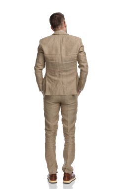 Bej takım elbiseli, gri saçlı, el ele tutuşan ve stüdyoda beyaz arka planda duran iş adamlarının arkasında.