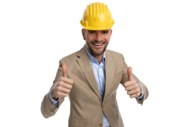 portrait of engineer man with helmet making thumbs up gesture and smiling in front of white background in studio