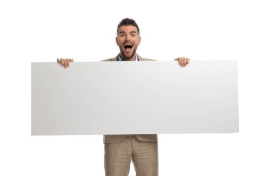 Heyecanlı genç adam beyaz arka planda boş tahtayı sunarken hevesli oluyor.