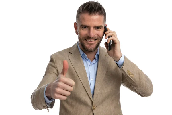 在演播室里 一个40多岁的面带微笑的男人在讲电话 用大拇指在白底前做手势 这是他的肖像 — 图库照片