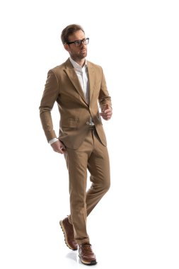 Çekici bir iş adamı beyaz arka planda gözlük takarak ve zarafetle yoluna devam ediyor.