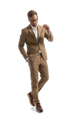 Seksi iş adamı bir eli cebinde yürürken dramatik oluyor ve beyaz arka plana bakıyor.