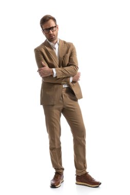 Havalı iş adamı kollarını göğsüne bağlıyor, gözlük takıyor ve beyaz arka planda poz veriyor.