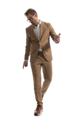 Çekici iş adamı aşağı bakıyor ve dramatik davranıyor, kameraya doğru yürüyor. 