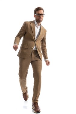 Havalı iş adamı kendi yolunda dikkatle yürüyor ve beyaz arka planda gözlük takıyor.