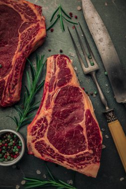İki parça kırmızı etten oluşan üst masa çatal bıçak takımının yanında biberiyeyle pişiriliyor ve demir masanın üzerinde tuz ve biber parçacıkları serpiştiriliyor.