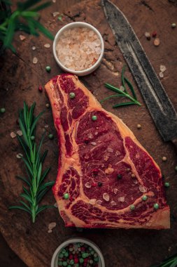 Eski kesme tahtasının tepesinde kırmızı et, yeşil biberiye ve tuz ve biber serpiştirilmiş.