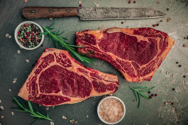 Lezzetli yemek kavramı, iki pişmemiş kırmızı biftekle biraz tuz ve biber, biberiye ve demir masanın üstüne koyulan malzemelerle hazırlanıyor.