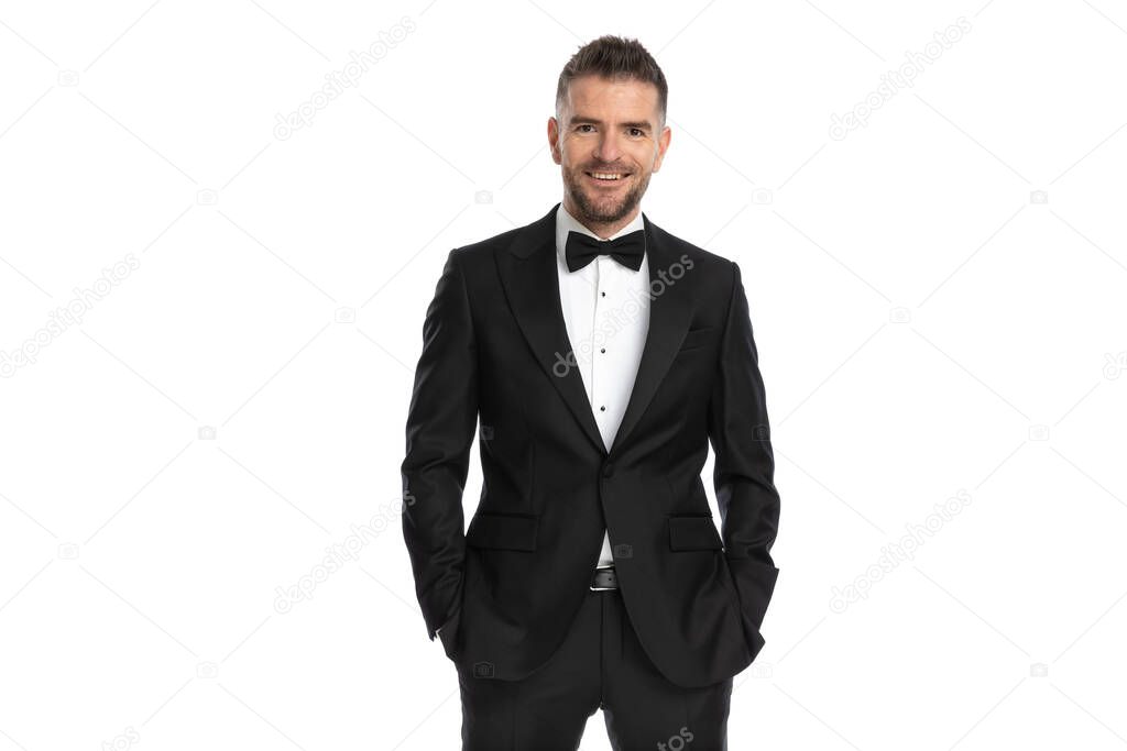 happy businessman smiling at the camera and holding hands in pocket against white background