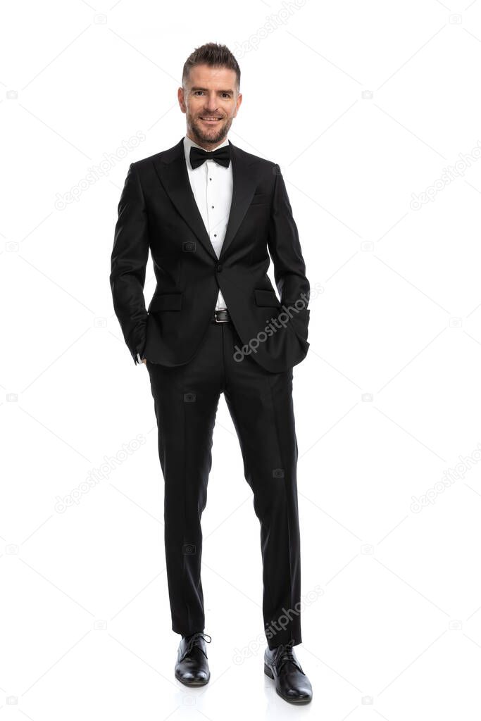 handsome businessman holding hands in pocket and posing with a smile on his face against white background