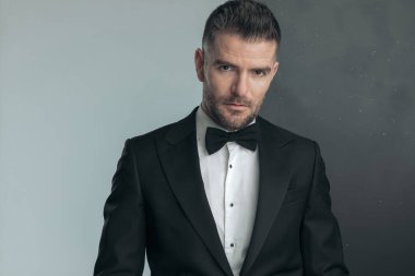 Yüzünde sert bir ifade olan çekici manken gri ve siyah arka plana karşı poz veriyor.