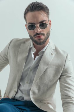 Gri arkaplan önünde özgüvenli bir şekilde poz verirken, bağcıksız gömlek ve gözlük takan yakışıklı iş adamının portresi 