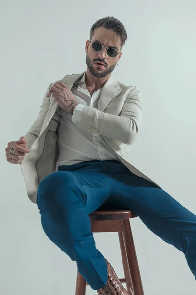 Sexy Young Man Glasses Arranging Jacket Sitting Wooden Chair Grey — Stok fotoğraf