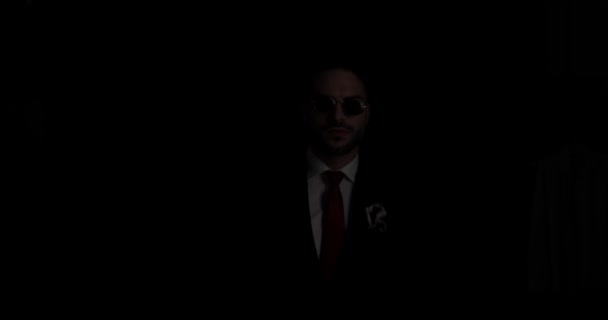 性感的留着胡子的男人 戴着眼镜修红领带 一边看一边在黑暗的背景下引人注目 一边消失了 — 图库视频影像