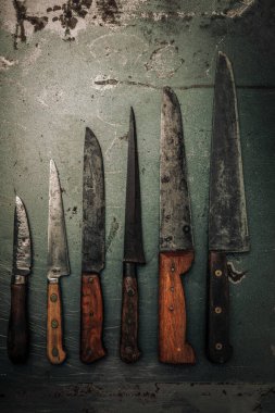 vintage collection of knives with wooden handle and carbon steel blade on top of rusty metallic background
