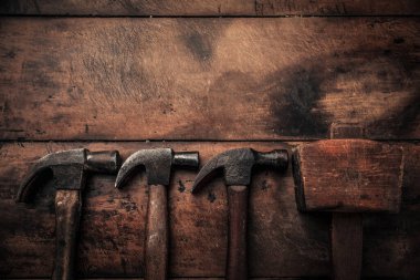 concept of carpentry manual work illustrating by old rusty mallets with copy space above on rustic work bench 