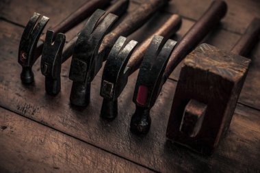 collection of carpentry hammers on top of old vintage workbench for manual work 