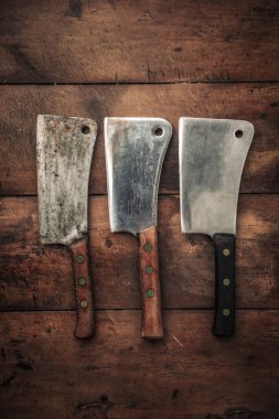 top view of three rusting hatchets for meat chopping with sharp blande and wooden handle on wooden table