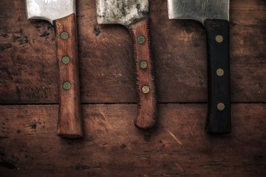 close up picture of three cleaver wooden kitchen knives on top of wooden table