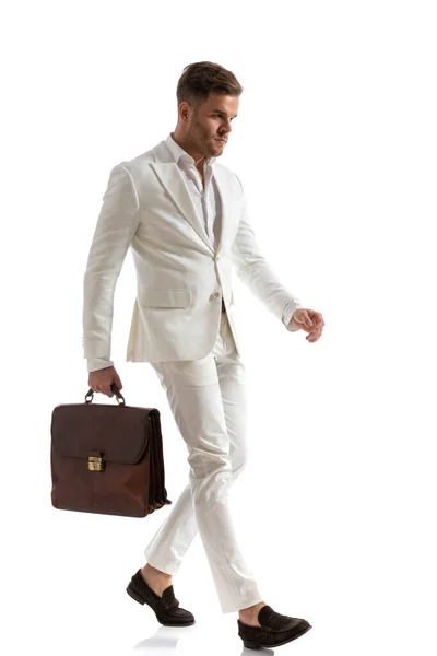 在演播室里 身穿白色西服的优雅年轻商人提着手提箱 独立行走在白色背景下的全貌照片 — 图库照片