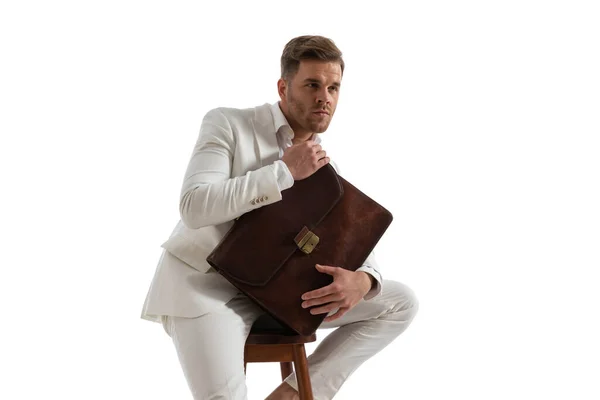 Eleganter Junger Geschäftsmann Weißen Anzug Mit Koffer Und Wegschauendem Blick — Stockfoto