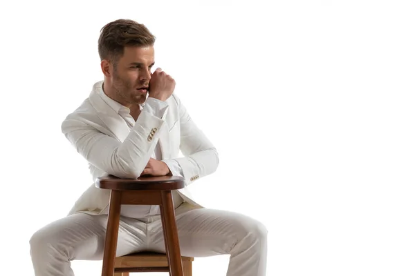Przystojny Siedzący Mężczyzna Białym Garniturze Trzymający Łokieć Krześle Patrzący Bok — Zdjęcie stockowe