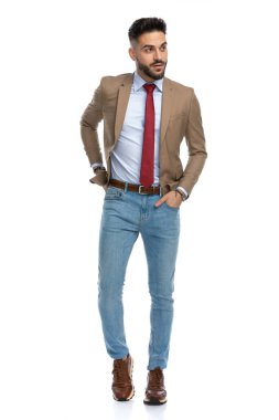 Kendine güveni tam bir adam. Ceplerinde el ele tutuşup stüdyoda beyaz arka planda yürürken yan tarafa bakıyor.