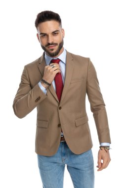 Stüdyoda beyaz arka planda mutlu ve kırmızı kravat takan, traşsız, seksi bir adamın portresi.