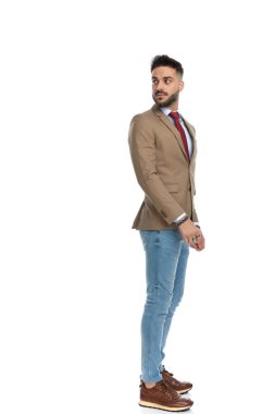 Yakışıklı adam kuyrukta beklerken omzunun üstünden bakıyor. Stüdyoda beyaz arka planda poz veriyor. Tüm vücuduyla.