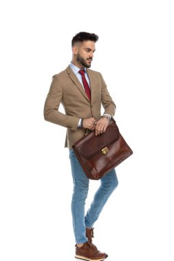 Stüdyoda beyaz arka planda poz veren, bavullu, tıraşsız, seksi adam.