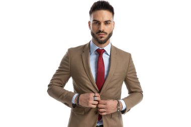 Kendine güvenen genç adamın portresi düzenleme ve düğme ceketi, stüdyoda beyaz arka planda poz