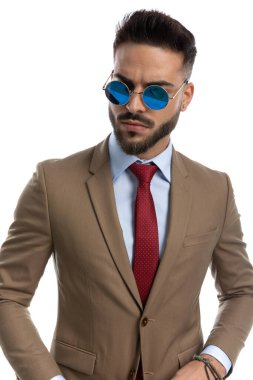 Kırmızı kravatlı ve geçmişe dönük güneş gözlüklü havalı iş adamının portresi atölyedeki beyaz arka planda rahatça poz veriyor.