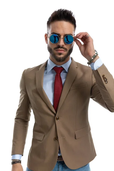 セクシーな髭を生やした男とジャケットと赤いネクタイを保持し 白い背景の前でサングラスを調整 肖像画 — ストック写真