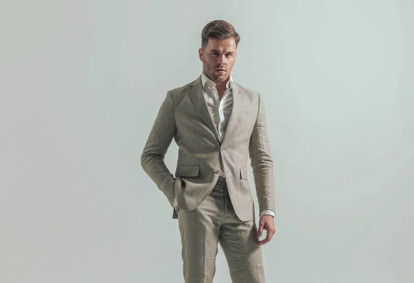 セクシーなスタイリッシュな男とともにオープン襟シャツ保持手でポケットと自信を持ってポーズの前にグレーの背景でスタジオ — ストック写真