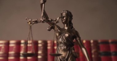 Üniversite odasındaki kitapların önündeki iki geniş hukuk kaynağı için elinde terazi olan gözleri bağlı bir kadın heykeli kapatın.