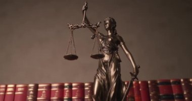 Gözü bağlı bronz tanrıça tarafından resmedilmiş adalet kavramı. Kılıç ve skalayı tutuyor, bir üniversite odasında kitaplardan yapılmış sıranın önünde dönüyor ve hareket ediyor.