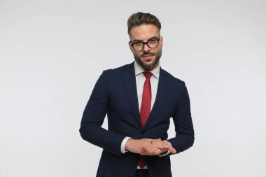 Tıraşsız iş adamının portresi. Gözlüklü, el ele tutuşan ve avuçlarını ovuşturan. Stüdyoda beyaz arkaplan önünde kendinden emin ve soğukkanlı.