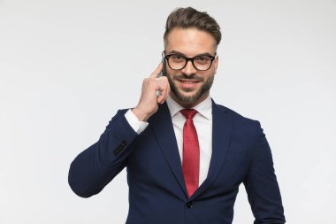 Gözlüklü mutlu iş adamının portresi telefonla konuşuyor ve stüdyoda beyaz arka planda gülümsüyor.