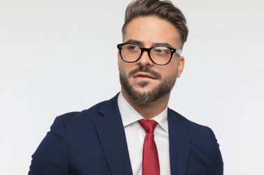 Genç sakallı bir adamın, beyaz arka planda dudaklarını ısırarak bakışlarını kapattığı bir resim.