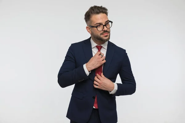 Lacivert Gözlüklü Şık Bir Işadamı Kırmızı Kravatı Düzeltirken Dikilirken Stüdyoda — Stok fotoğraf
