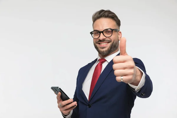 Attraktiv Ung Man Med Glasögon Håller Mobiltelefon Och Göra Tummen — Stockfoto